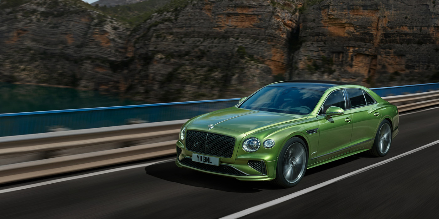 Exclusive Cars Vertriebs GmbH Bentley New Flying Spur Speed v8 hybrid sedan driving dynamically on a mountain road in Tourmaline Green paint