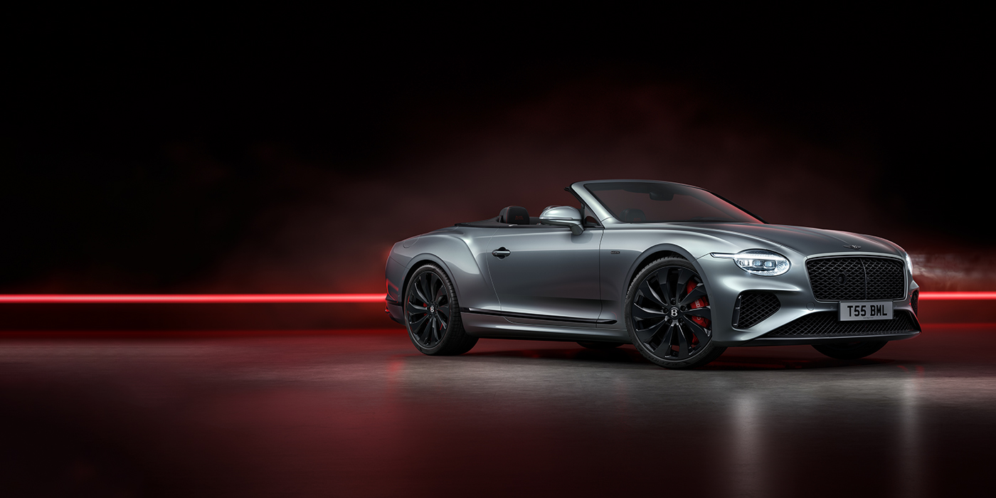 Exclusive Cars Vertriebs GmbH Bentley Continental GTC Black Edition convertible front three quarters in Hallmark silver against a dark grey and red background
