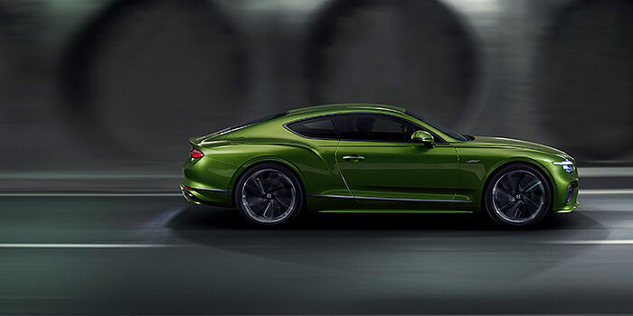  Exclusive Cars Vertriebs GmbH Bentley Continental GT coupe in Tourmaline Green paint driving in profile on a dark road