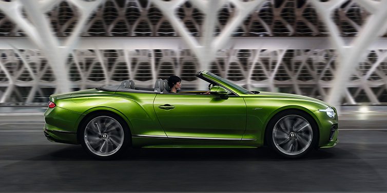 Exclusive Cars Vertriebs GmbH Bentley Continental GTC Speed convertible side profile in Tourmaline Green paint driving dynamically on a bridge at night