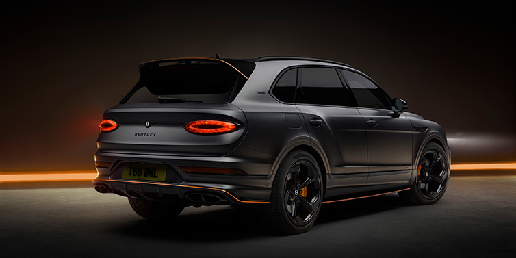 Exclusive Cars Vertriebs GmbH Bentley Bentayga S Black Edition SUV rear three quarter in Anthracite Satin paint against a dark red and yellow background