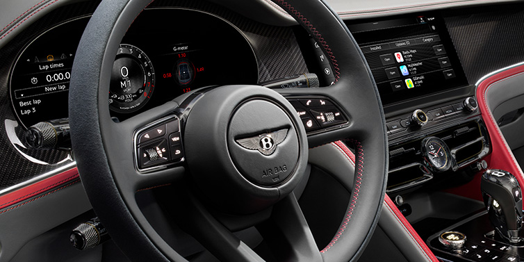 Exclusive Cars Vertriebs GmbH Bentley Flying Spur Speed sedan front interior detail showing steering wheel and driver screens surrounded with Hotspur red and Gravity Grey hides